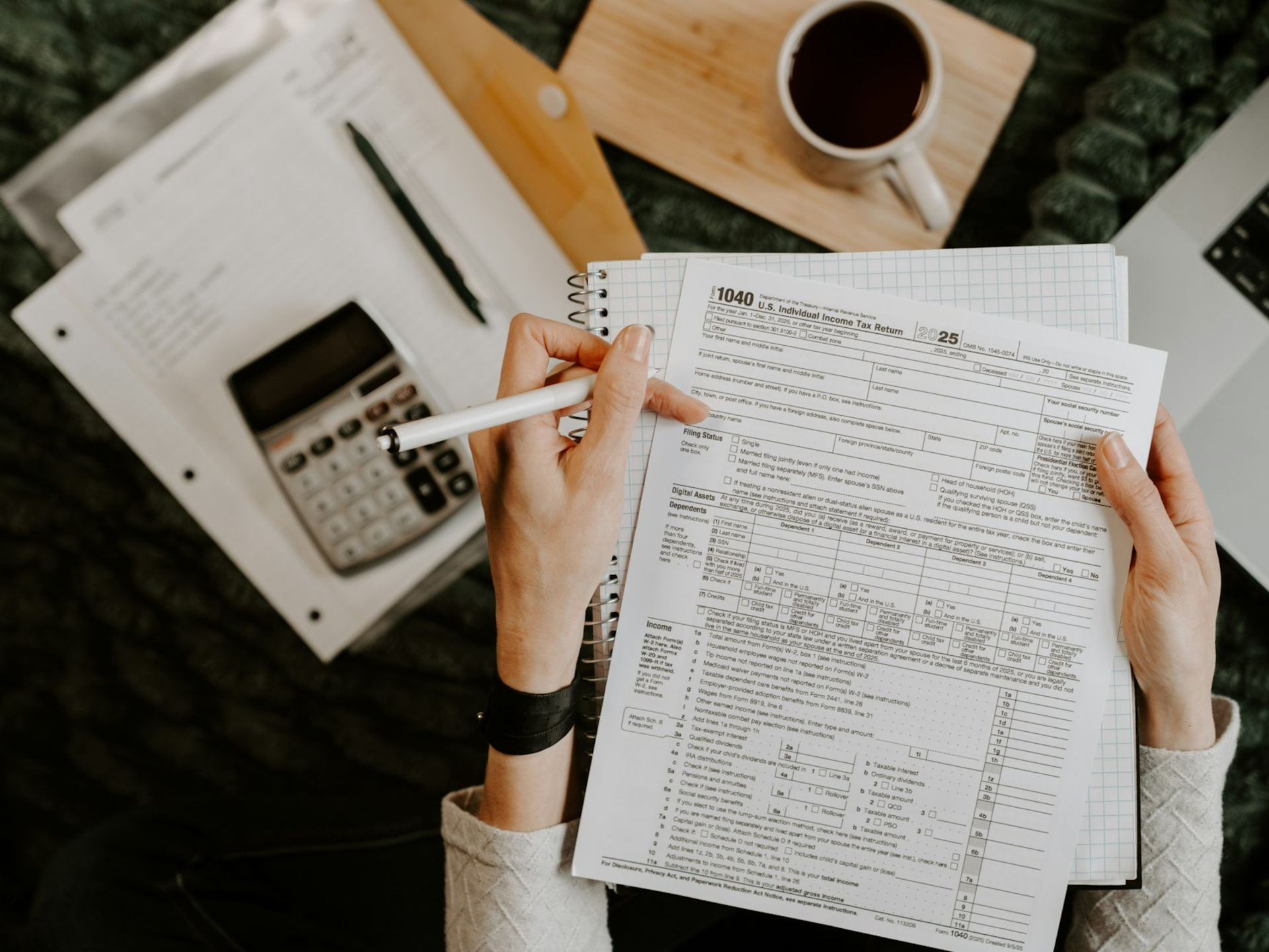 Person reviewing documents with calculator and laptop